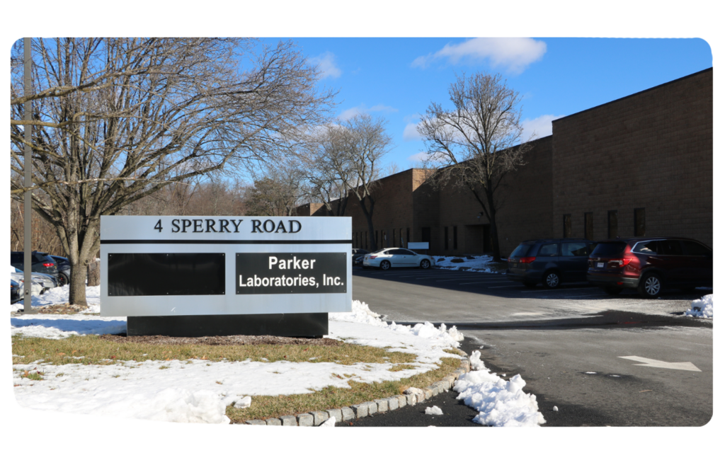 Exterior view of Parker Laboratories headquarters building at 4 Sperry Road, Fairfield, NJ. Modern office building with glass windows and company signage visible